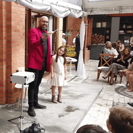 Mago profesional realizando un truco de magia interactivo con niños en una fiesta familiar en Caracas.